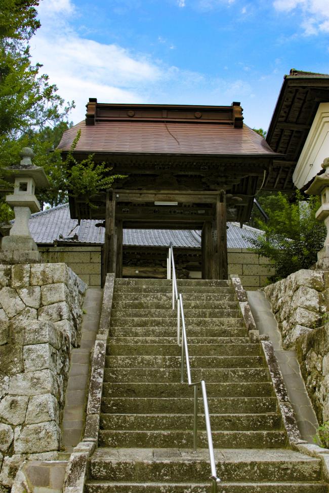 石垣の階段の下から山門を見上げている写真