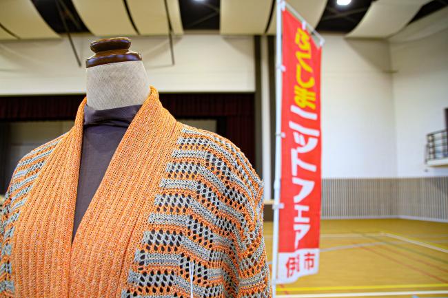 ふくしまニットフェアというのぼり旗の手前でオレンジ色のニットを着ているマネキンの写真