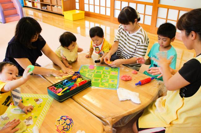 霊山子育て支援センターで遊ぶ親子と保育士の写真