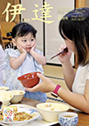 市政だより8月号の表紙はこども食堂で味噌汁を食べて、母親に向けて「おいしい」の表情を見せる子どもの写真です
